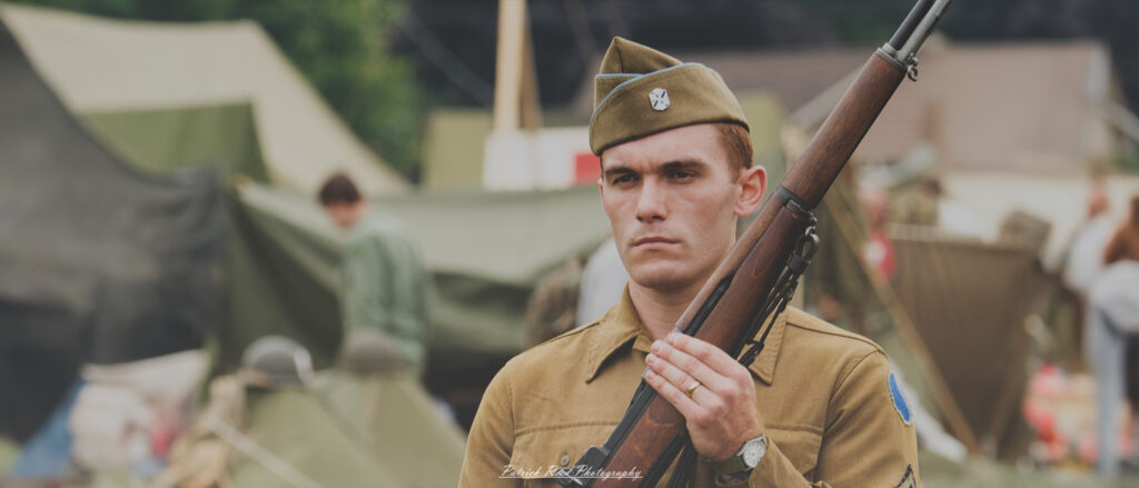 A soldier standing at attention with an M1 Garand rifle, his posture straight and eyes forward. The scene highlights the soldier's discipline and readiness, embodying the professionalism and pride of military service.